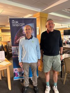 2 men standing inn front of banner